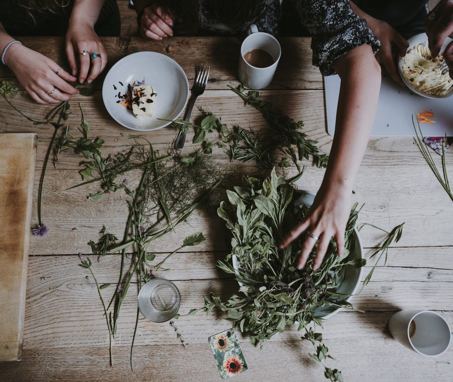 Manos con hierbas sobre la mesa del taller